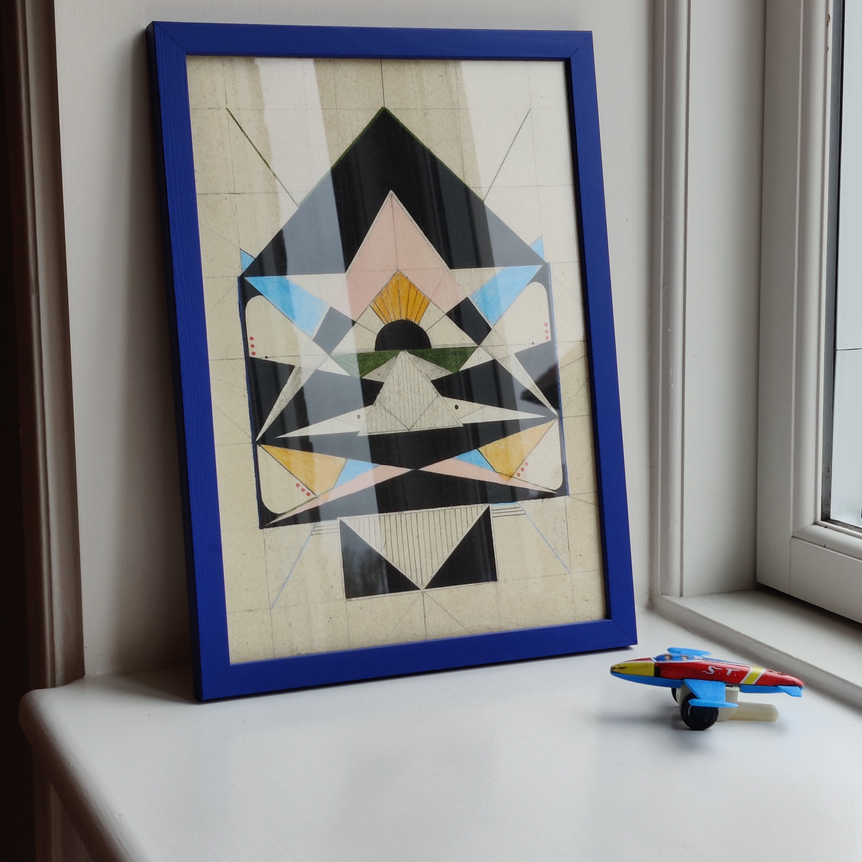 Cardboard Spaceship arrow on a windowsill with a toy plane below