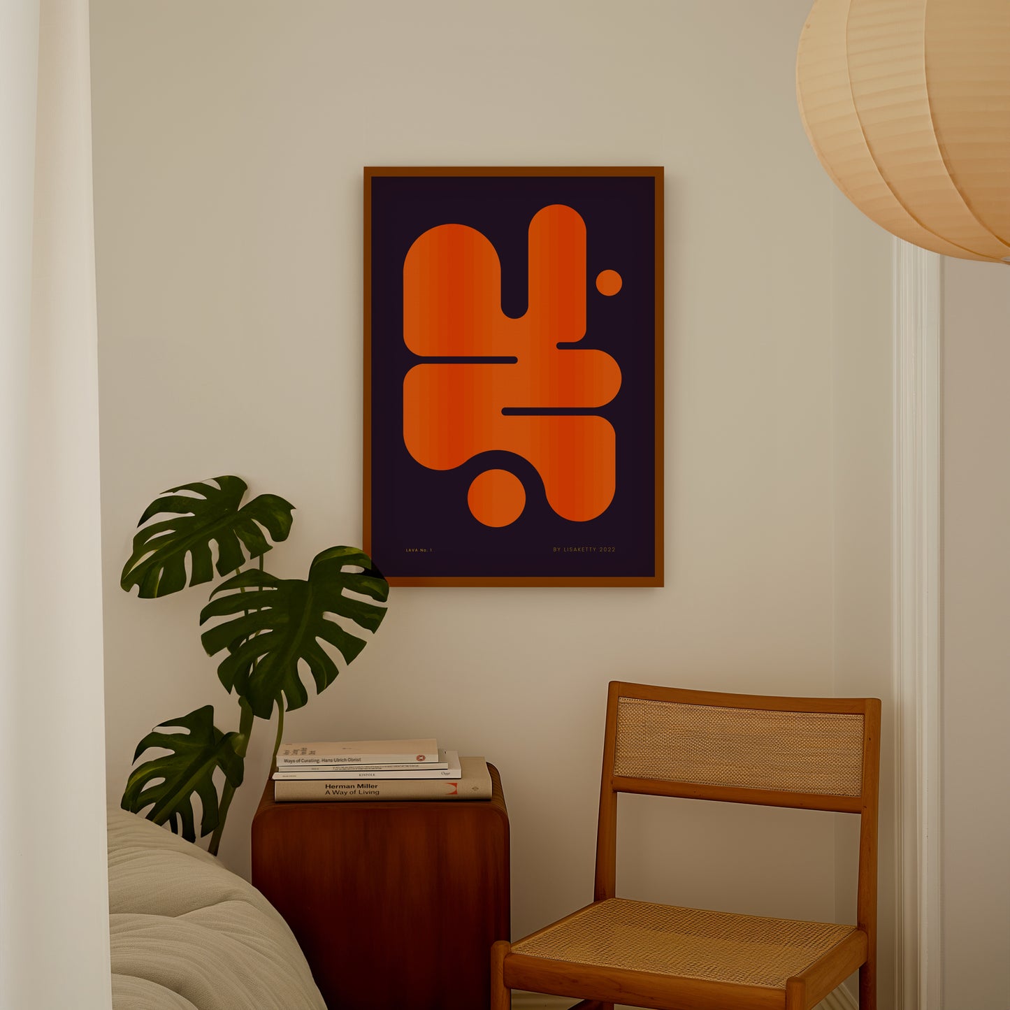 Abstract orange and black art piece on a wall above a wooden side table with books and a plant.