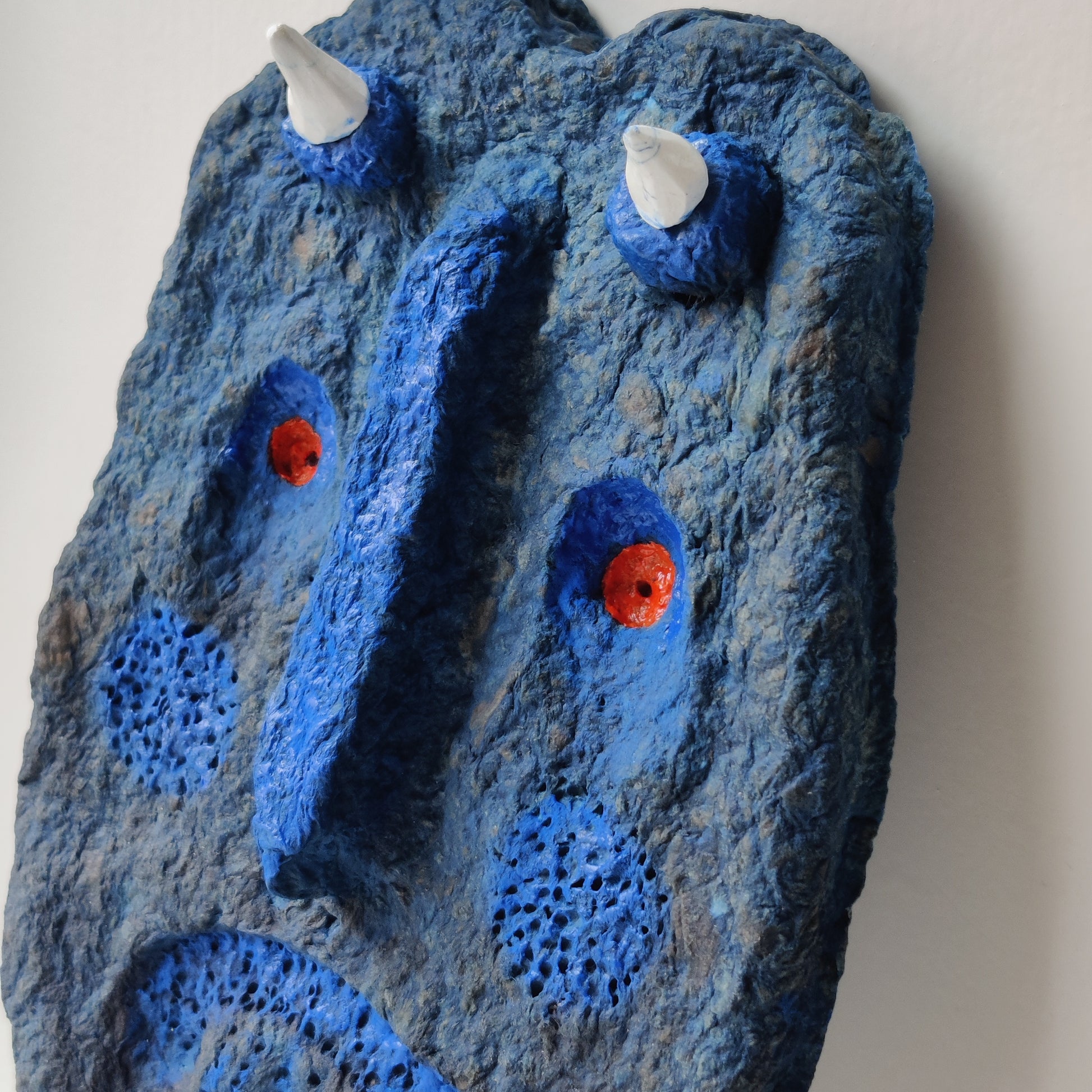 I have been mixing blue in the cardboard clay and have been using blue and orange acrylic paint. He also uses a fast-drying white clay painted with white polish to give it some shine, and the same goes for some spots in the blue paint. 